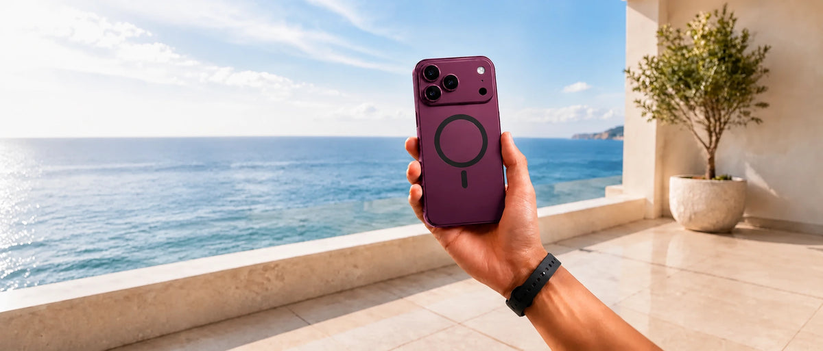 Burgundy magnetic phone case with a black charging ring held by the ocean.